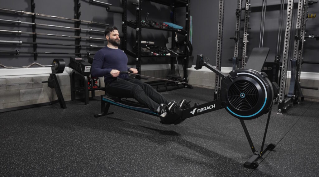 Man using a Merach Novarow R50 rowing machine in a gym setting.